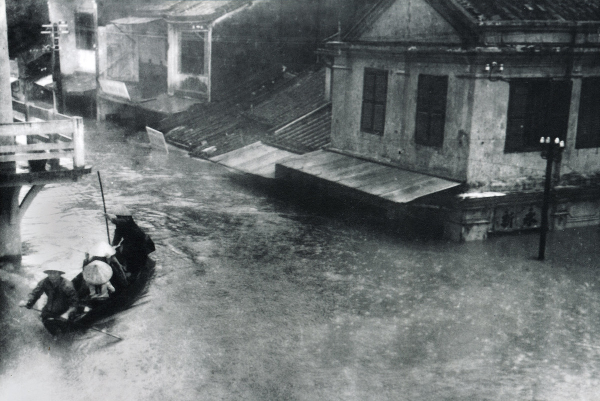Một bức ảnh không rõ tác giả, ghi lại cảnh một con đò chở khách khi nước dâng đến sát tầng lầu các ngôi nhà ở phố cổ Hội An năm 1964.