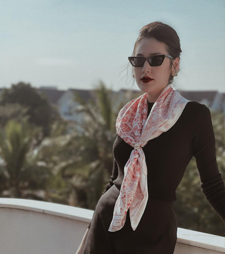 Diện nguyên set đồ đen với áo dệt kim và chân váy, Á hậu Tú Anh lại khéo nhấn nhá style với 1 chiếc khăn quàng cổ. Mẫu khăn mang tông màu trắng là chủ đạo với các họa tiết nhỏ xinh nên nhìn tổng thể vẫn mang nét tối giản, nền nã.