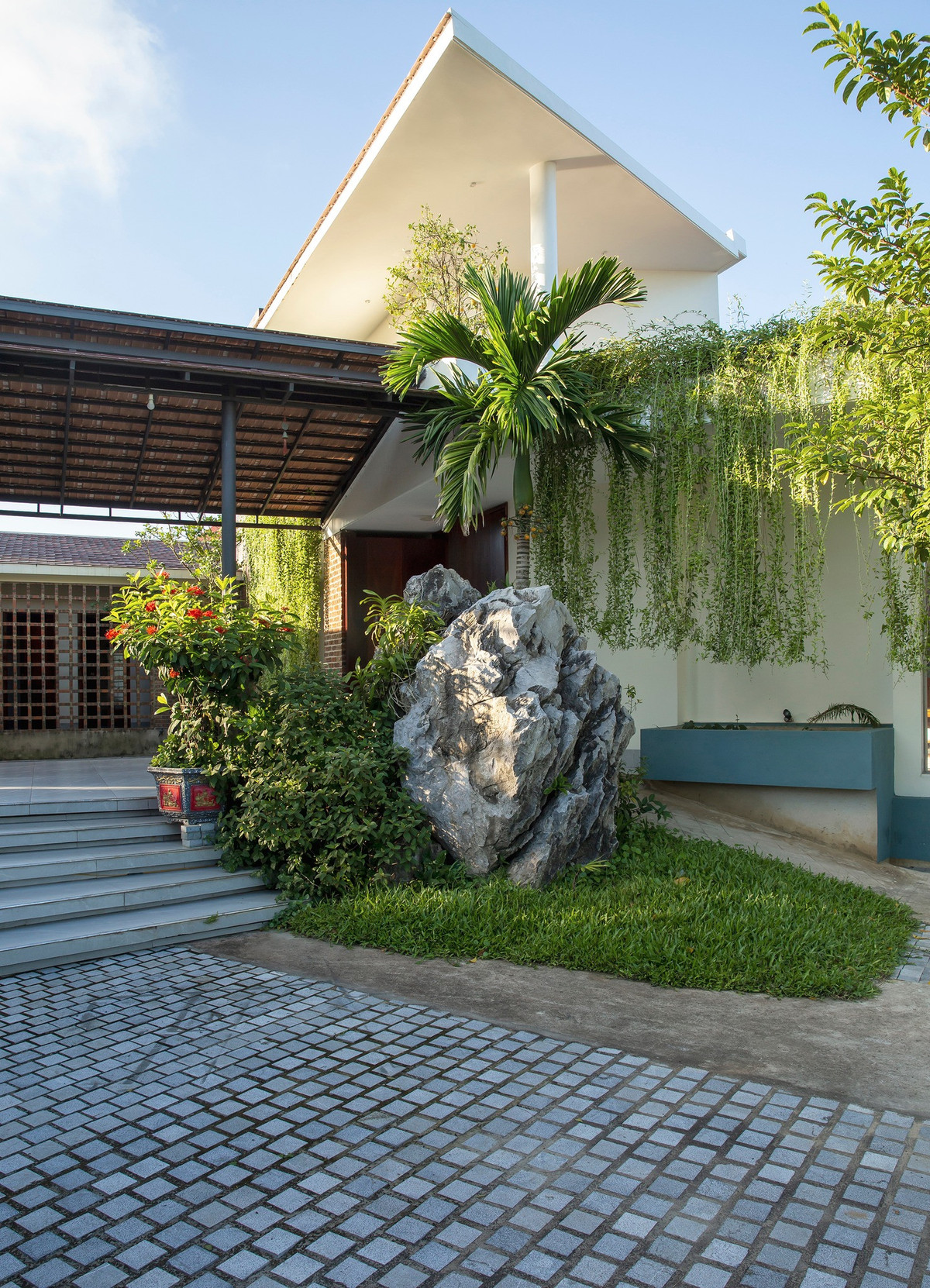 Với diện tích đất 1200m2 anh Sơn bố trí tầng trệt diện tích 250m2 và phần đất còn lại để làm sân chơi, cây xanh và vườn rau. Việc phủ xanh công trình, anh ưu tiên sử dụng cây ăn trái bản địa, đan xen các mảng xanh hoa cỏ, tiểu cảnh. Hệ cây cúc tần treo sử dụng như một rèm chắn nắng tự nhiên. Vườn rau bố trí xung quanh ngôi nhà để chủ nhân có thể gieo trồng rau sạch phục vụ đời sống sinh hoạt hằng ngày.