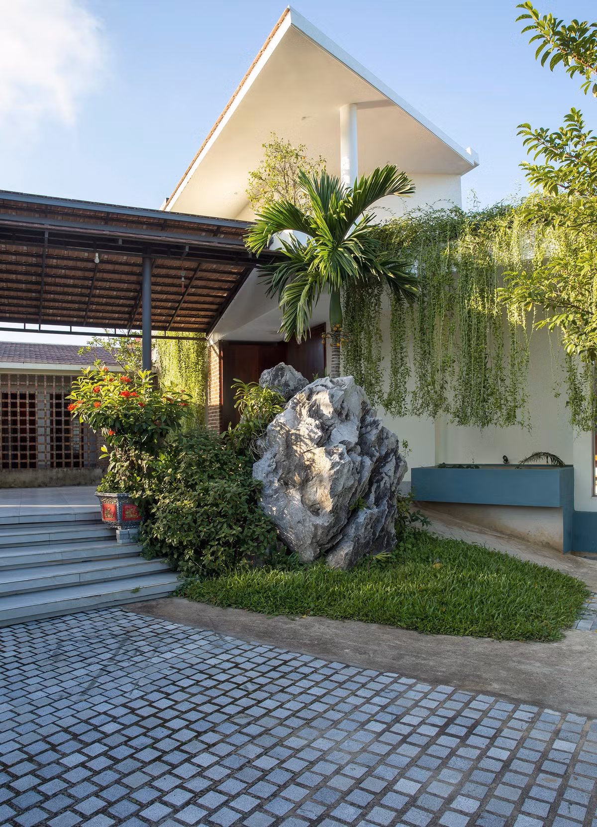 Với diện tích đất 1200m2 anh Sơn bố trí tầng trệt diện tích 250m2 và phần đất còn lại để làm sân chơi, cây xanh và vườn rau. Việc phủ xanh công trình, anh ưu tiên sử dụng cây ăn trái bản địa, đan xen các mảng xanh hoa cỏ, tiểu cảnh. Hệ cây cúc tần treo sử dụng như một rèm chắn nắng tự nhiên. Vườn rau bố trí xung quanh ngôi nhà để chủ nhân có thể gieo trồng rau sạch phục vụ đời sống sinh hoạt hằng ngày.