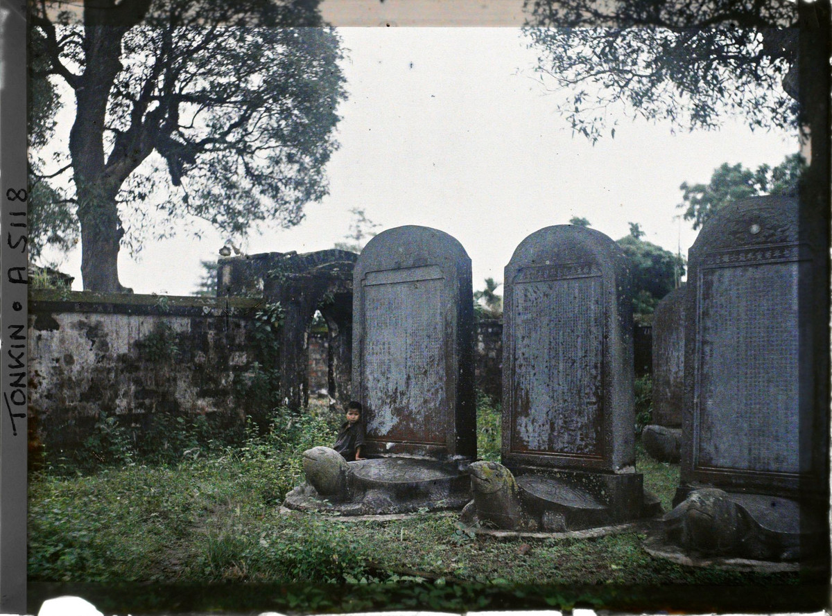 Em bé bên bia đá rêu phong.