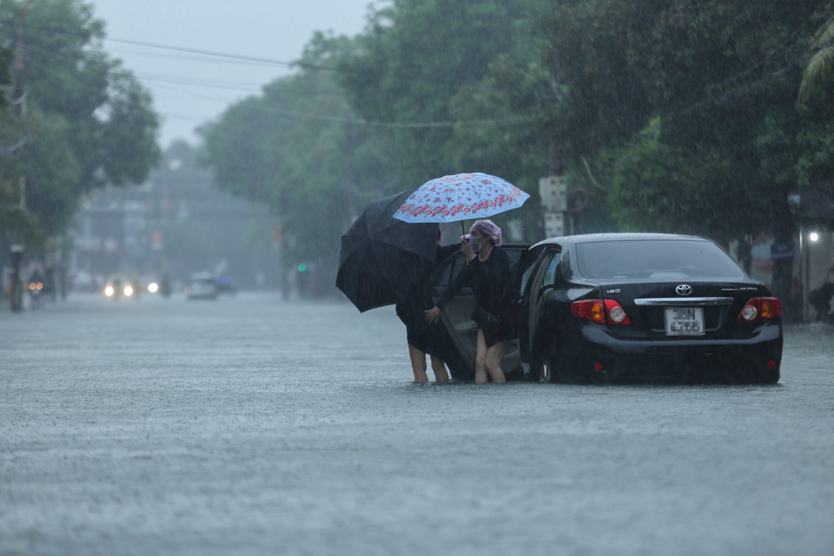 Một ôtô cố băng qua đoạn đường ngập nhưng bị chết máy, người ngồi trong xe đành mở cửa ra ngoài và gọi cứu hộ.