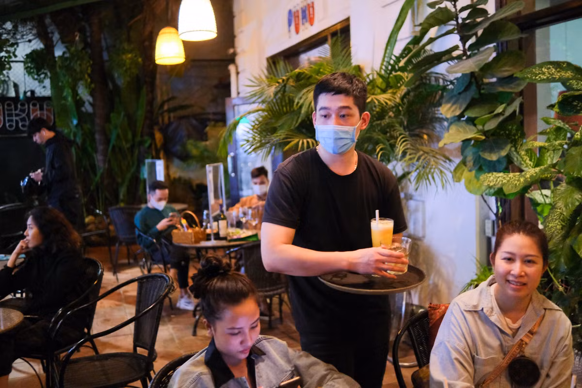 Phạm Văn Tuấn (quản lý tại quán Puku) bận rộn sắp bàn, theo dõi đơn order, bưng bê món. Anh cho biết số lượng khách ghé quán dần đông lên vào buổi tối. Thông thường, ca đêm của quán có 6-7 nhân viên làm việc nhưng trong ngày đầu chỉ còn một nửa. Thiếu người, anh kiêm luôn chân chạy bàn, thu ngân, phụ giúp pha chế để kịp phục vụ khách. "Mệt nhưng vui là cảm giác của mình sau thời gian dài công việc gián đoạn vì dịch bệnh", anh nói.