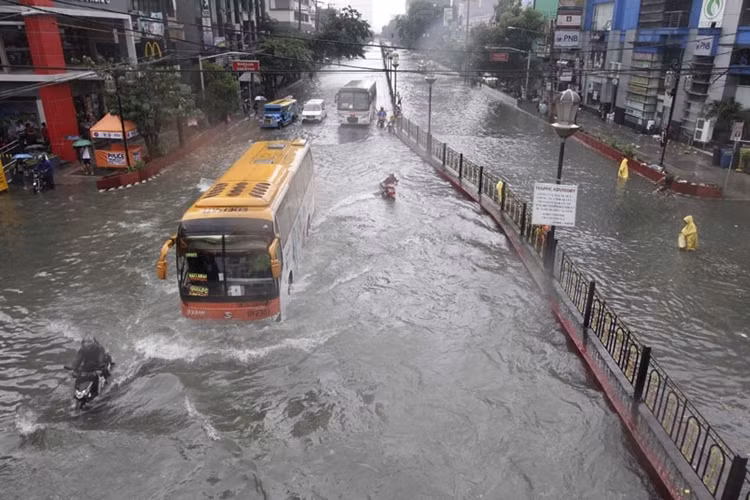 Xe máy cố rẽ nước đi lại trên đường phố Manila...