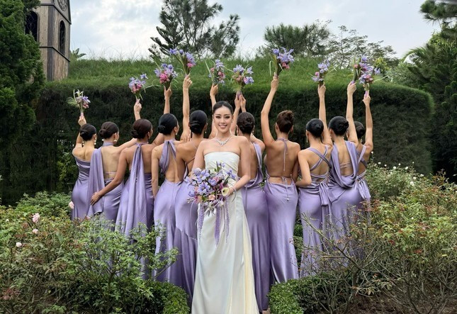 Trong bộ ảnh cưới trước đó, Hoa hậu Khánh Vân mặc váy trắng, tay ôm hoa tím - màu hoa giống vương miện Hoa hậu Hoàn vũ Việt Nam 2019. Hình ảnh loạt phù dâu khoe lưng trần, giấu mặt khiến nhiều người thắc mắc.