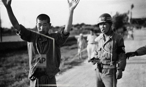 Cảnh sát quân sự Hàn Quốc dẫn giải tù binh Triều Tiên với khẩu súng ngắn trong tay. Ảnh chụp ngày 21/7/1950.