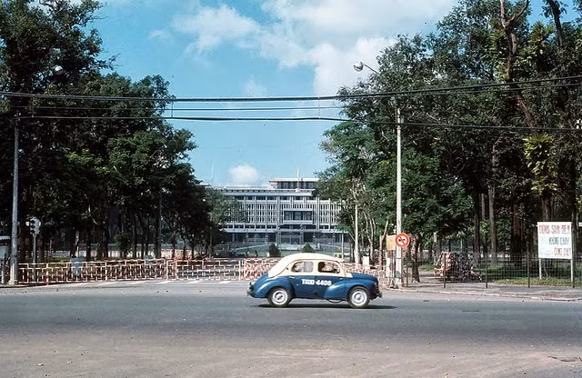 Một chiếc xe taxi đi qua con đường rộng thênh thang trước mặt Dinh Độc Lập.