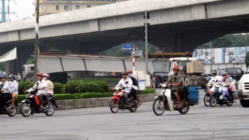 Xe chở thanh dầm chạy dưới một cây cầu vượt.