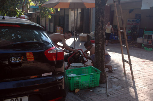 2 người đàn ông khẩn trương đổ nhớt cho máy phát điện trên đường Tô Hiệu, Nghĩa Tân, quận Cầu Giấy.