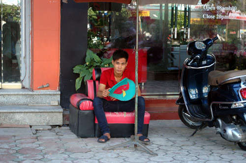 Nhân viên bảo vệ nhà hàng ở phố Trần Thái Tông sử dụng quạt "cầm tay" vì không có điện.