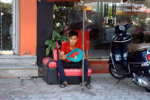 Nhân viên bảo vệ nhà hàng ở phố Trần Thái Tông sử dụng quạt "cầm tay" vì không có điện.