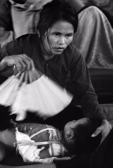 Người mẹ chăm sóc cho đứa con bị thương do chiến sự trong một bệnh xá ở Quảng Ngãi năm 1967. Ảnh: Philip Jones Griffiths/ Magnum.