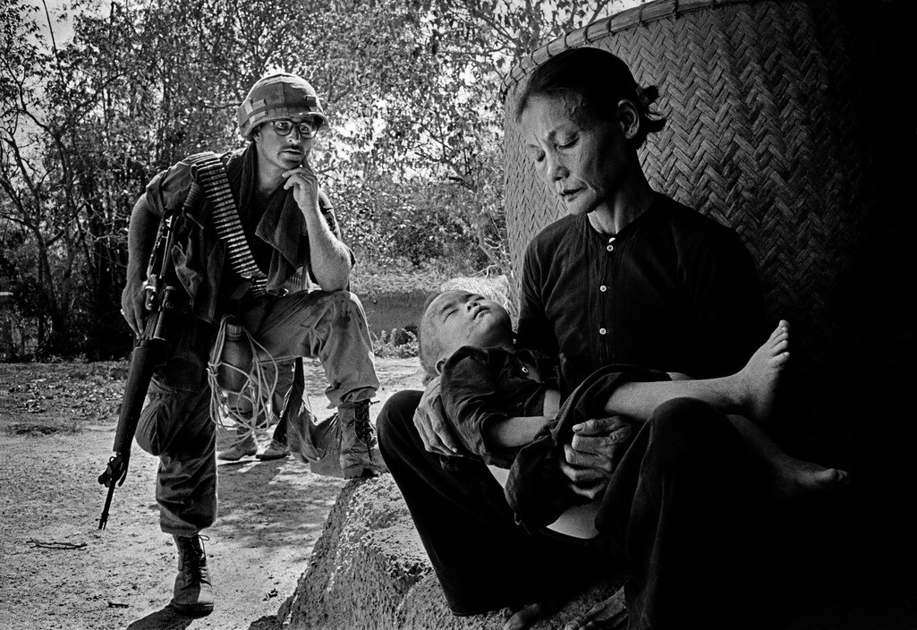 Lính Mỹ quan sát một cụ bà bế trên tay đứa cháu nhỏ trong một cuộc càn quét ở Quảng Ngãi năm 1967. Ảnh: Philip Jones Griffiths/ Magnum.