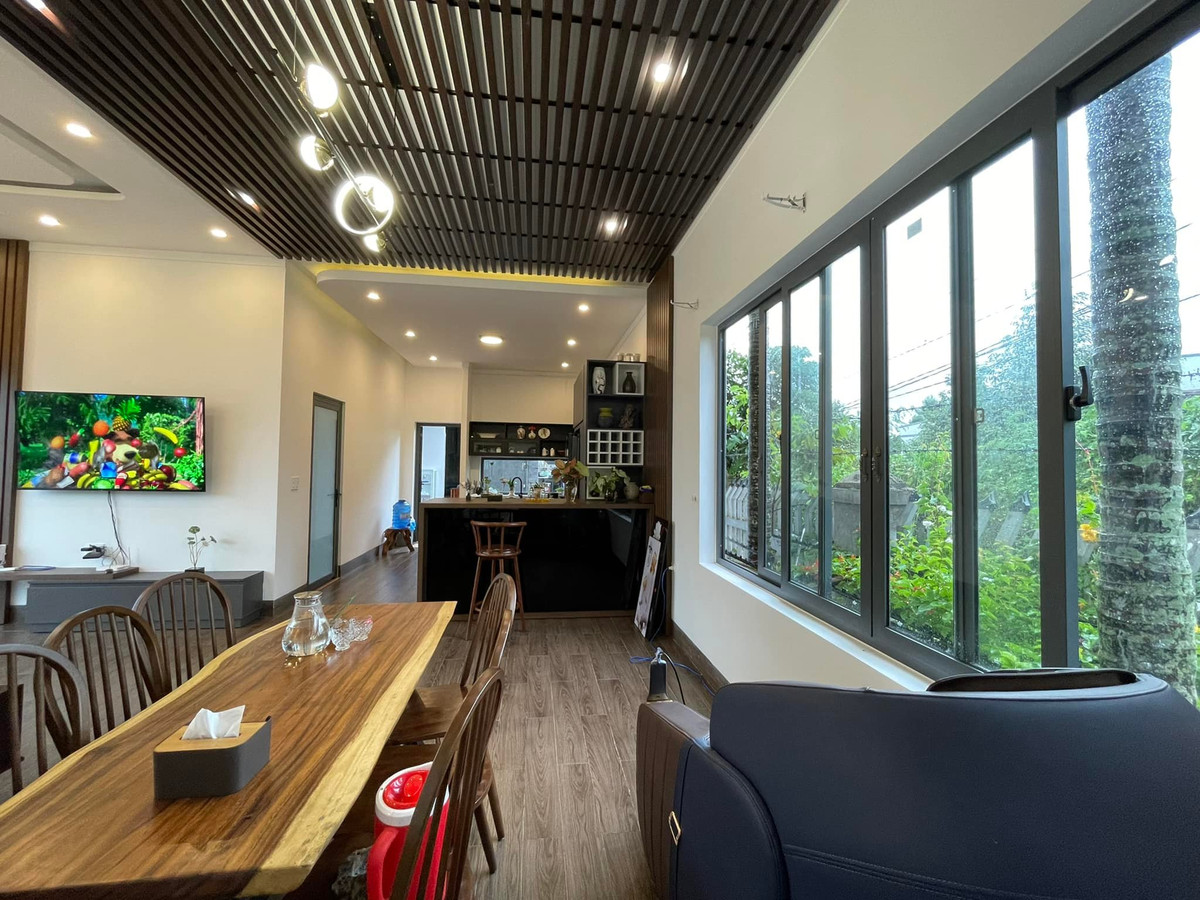 Phòng khách, bếp và bàn ăn tạo thành mạch liên kết, giúp các thành viên có thể quan sát nhau mọi lúc, mọi nơi. Dù đứng ở bàn ăn, phòng khách, ai cũng nhìn ra được khoảng sân vườn rộng và xanh mướt.