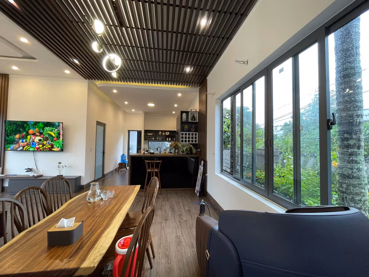 Phòng khách, bếp và bàn ăn tạo thành mạch liên kết, giúp các thành viên có thể quan sát nhau mọi lúc, mọi nơi. Dù đứng ở bàn ăn, phòng khách, ai cũng nhìn ra được khoảng sân vườn rộng và xanh mướt.