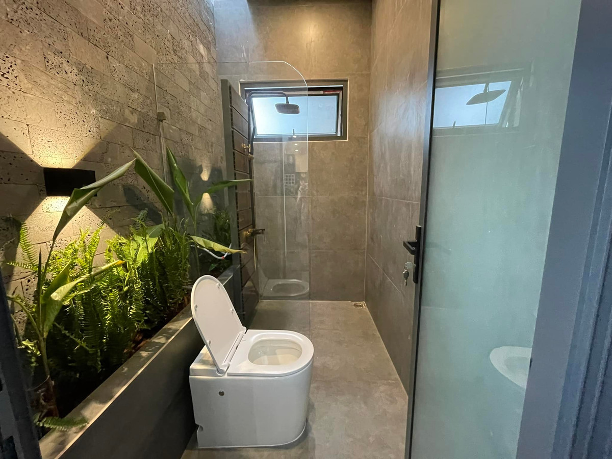 Phòng vệ sinh chung có vách tắm kính và bồn cây dưới giếng trời nhỏ. Giếng trời có tác dụng lọc không khí, đối lưu gió và hút mùi hôi hiệu quả.