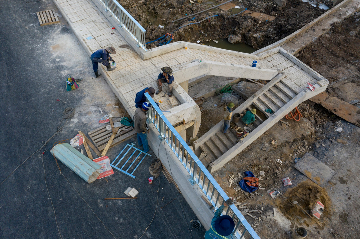 Hàng chục công nhân của nhà thầu chia nhau thi công các hạng mục cuối cùng của dự án như lắp lan can, khe co giãn, lát gạch trên lối đi bộ... để sẵn sàng cho lễ thông xe vào ngày 15/10.