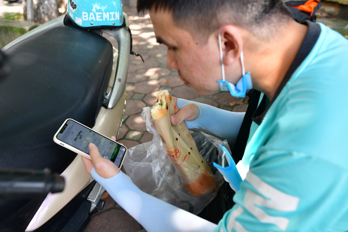 Anh Doãn Bảo Trung, shipper công nghệ, tranh thủ dùng bữa trước khi bắt đầu mở app nhận đơn. “Từ 11-12h là thời gian nhận đơn cao điểm, anh em shipper chúng tôi thường ăn sau giờ đó. Vào những trưa nắng nóng, chạy ngoài đường nhiều khiến tôi mệt mỏi, nên cứ phải lót dạ trước đã”, anh Trung nói.