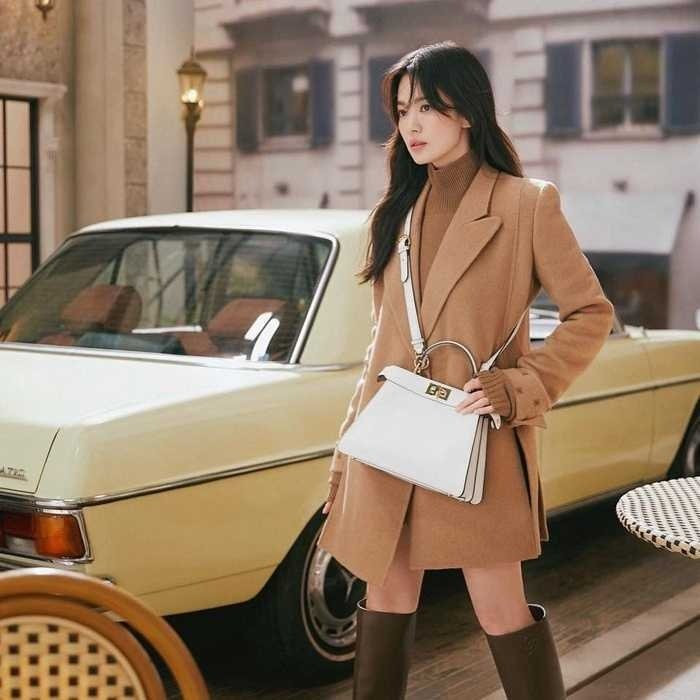 Song Hye Kyo lại chọn lên đồ với tông màu nâu đất - xu hướng hot trend của mùa thu đông. Nữ diễn viên kết hợp áo len cổ lọ cùng áo khoác dạ dáng dài với boots cao cổ đồng điệu