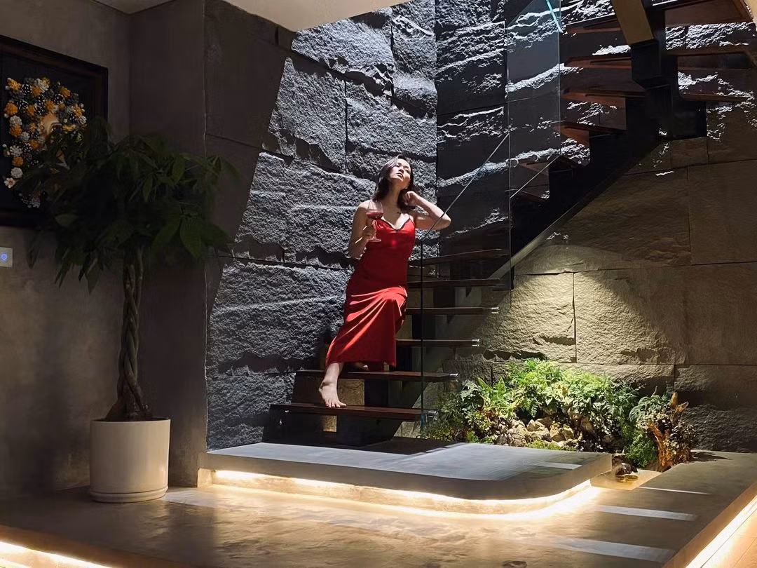 Cầu thang lên tầng 2 với tay vịn kính sang trọng, phần sàn gắn đèn led chiếu sáng, bờ tường sử dụng vật liệu đặc biệt tạo độ nhám để tăng sự độc đáo.