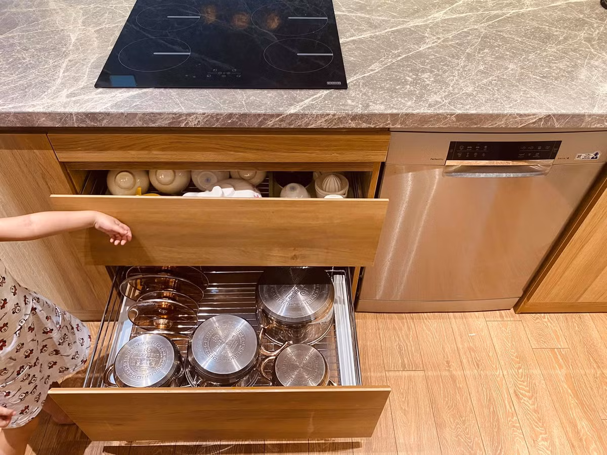 Máy rửa bát và hộc đựng bát nằm dưới bếp từ, thuận tiện cho việc lấy đồ nấu nướng và vệ sinh.