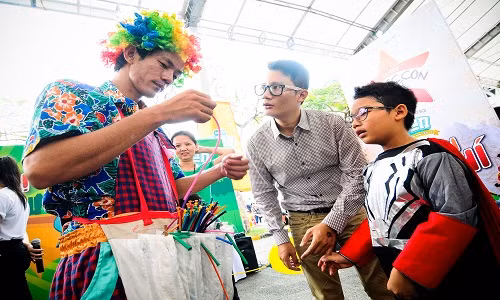 Sau đó, Tê Giác rủ bố Hoàng Bách sang quầy bên cạnh học cách làm bong bóng cùng chú hề vui nhộn. Hai bố con tròn xoe mắt học hỏi những “tuyệt chiêu” từ nghệ nhân bong bóng.