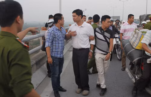 Trước đó, cơ quan CSĐT, CATP HN khám xét khẩn cấp trụ sở thẩm mỹ viện Cát Tường, rồi bắt khẩn cấp người này. Ảnh: hai cảnh sát hình sự mặc thường phục kẹp sát hung thủ, đề phòng đối tượng nhảy cầu