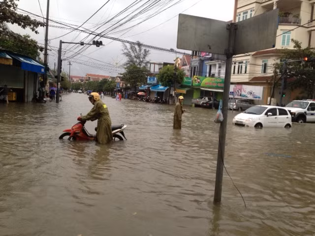 Một CSGT TP. Hà Tĩnh đang giúp đỡ người dân lưu thông qua đoạn nước ngập nặng. Ảnh: Đời sống và Pháp luật.