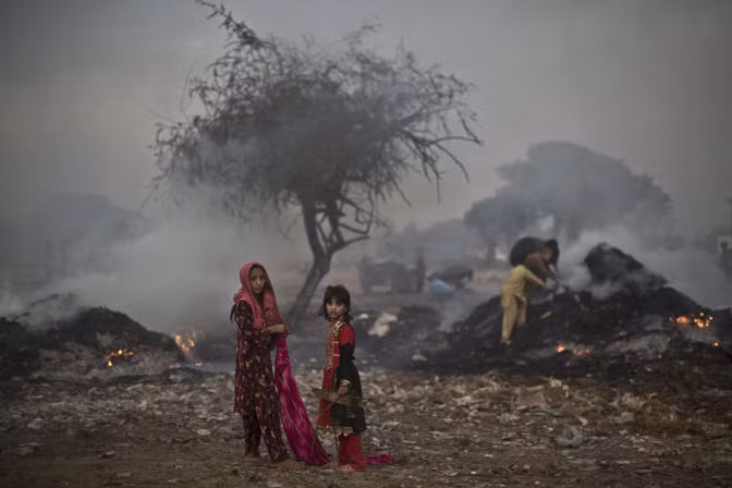 Một nhóm trẻ em Pakistan cố gắng nhặt nhạnh mảnh gỗ vụn xung quanh đám gỗ cháy dở trên khoảng đất trống ngày 4/10.