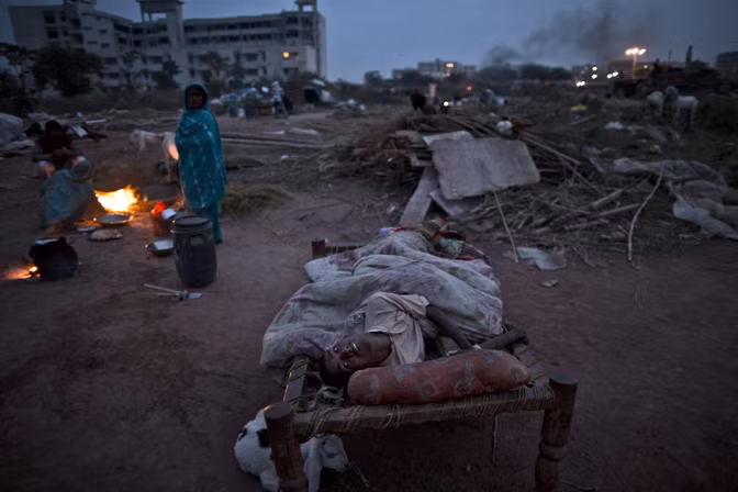 Một thiếu niên tật nguyền nằm trên chiếc chõng tre ngoài trời ngay gần đống đổ nát sau khi ngôi nhà của em bị đập.