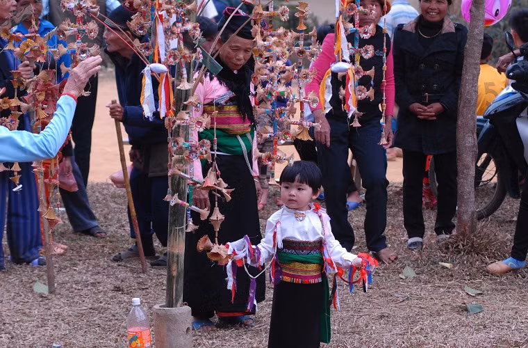 Một em bé với trang phục truyền thống của dân tộc cũng tập múa hoa.