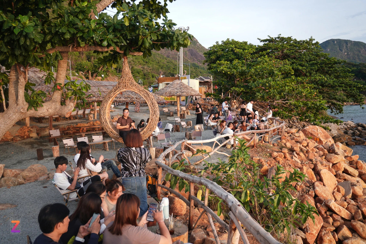 Khoảng 5h30, những chiếc bàn ghế được bày san sát cạnh bên bờ biển bắt đầu kín khách. Quán cà phê được trang trí theo phong cách mộc mạc với những chiếc bàn làm từ khúc gỗ, tảng đá, ghế gấp gọn, chòi mái lá cùng những những tiểu cảnh tổ chim, xích đu cũng được làm bằng gỗ. Thức uống nơi đây có giá từ 30.000-40.000 đồng/món.