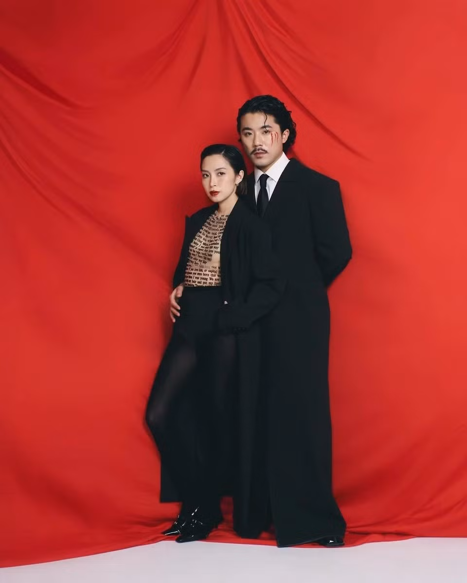 Vợ chồng Đức Triệu - Linh Bùi tôn vinh tính nữ qua set trang phục ton-sur-ton. Cả 2 cùng diện áo dạ dáng dài màu đen, theo đuổi xu hướng gender-fluid (linh hoạt giới). Đức Triệu chọn sơ mi trắng, caravat đen, quần lửng và vớ da chân chấm bi. Anh làm nền cho bà xã trong bộ hình này. Linh Bùi phối áo không tay trong suốt với quần lót cạp cao màu đen và vớ đồng màu. Cô nhiệt tình hưởng ứng mốt không quần được nhiều ngôi sao, tín đồ thời trang lăng xê. Cách kết hợp nội y tam giác và vớ da chân cũng từng được các minh tinh như Kylie Jenner hay Kendall Jenner ứng dụng thành công. Ảnh: @lovvin.family.