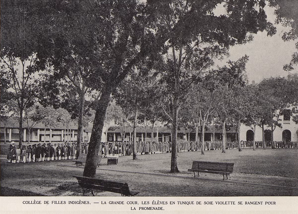 Các nữ sinh mặc áo dài lụa tím xếp hàng đi dạo trên sân trường Nữ trung học Bản xứ.