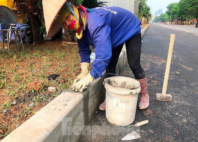 Trưa 26/4, mặc dù trời nắng nhưng một chị công nhân của đơn vị thi công vẫn miệt mài trà trát mạch bó vỉa dải phân cách, hoàn thiện phần đường mở rộng tại đoạn trước Học viện Chính trị Quốc gia Hồ Chí Minh.