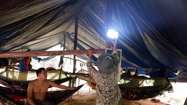 Ánh đèn điện sạc pin là nguồn ánh sáng duy nhất của anh em tại lán trại ở lại rừng khi về đêm.