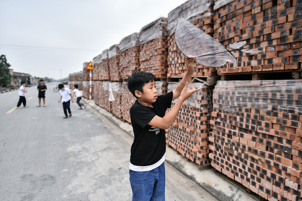 Bên ngoài nhà máy, vật liệu xây dựng được chất lên quây kín phần tường bao quanh. Cách nhà máy một con đường là khu vực người dân xã Liên Hồng sinh sống.