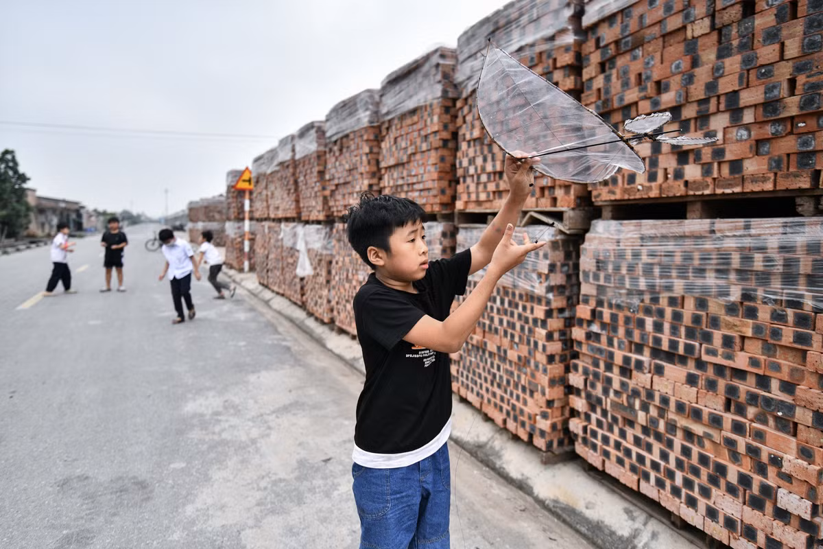 Bên ngoài nhà máy, vật liệu xây dựng được chất lên quây kín phần tường bao quanh. Cách nhà máy một con đường là khu vực người dân xã Liên Hồng sinh sống.