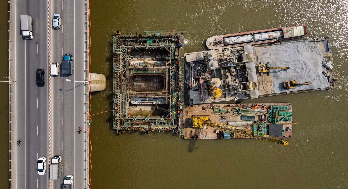 Để thi công trụ cầu vượt sông, nhà thầu phải đóng các cọc tường vây với chu vi khoảng 24 m. Chiều sâu tối đa là 10 m, sau đó một lớp bê tông dày 3 m được đổ xuống đáy cọc.