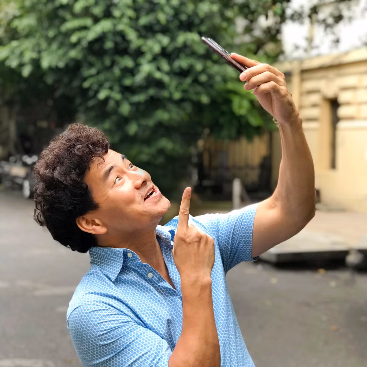 Xuân Bắc tạo dáng hài hước với điện thoại.