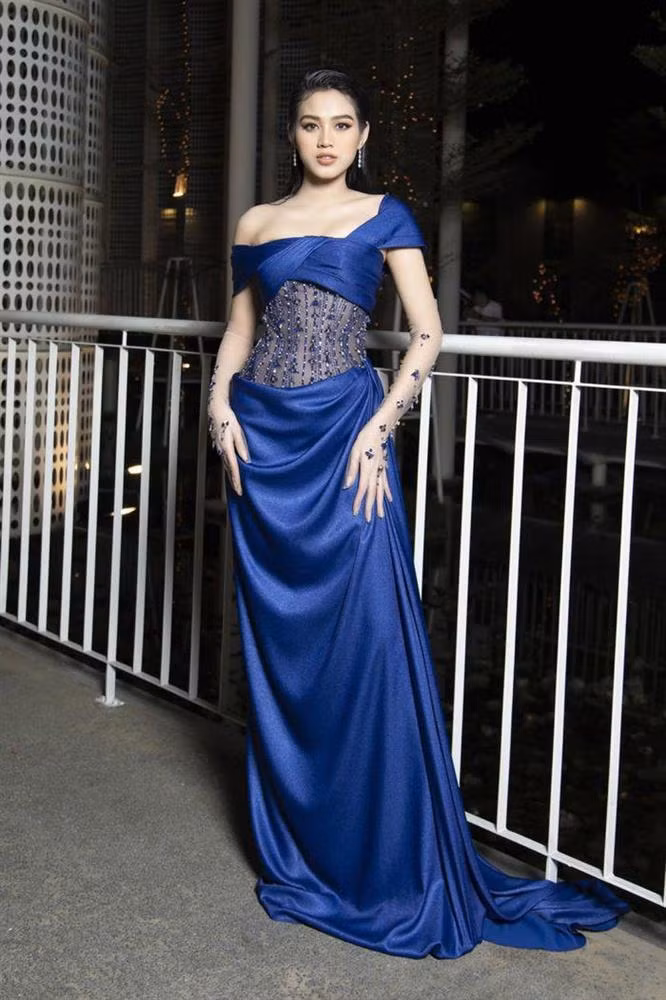 Nhìn từ xa, Đỗ Thị Hà trông không có gì để chê khi diện chiếc đầm xanh được thiết kế cầu kì với những đường nhún xếp ly 1 bên hông. Chiếc đầm cũng trở nên lấp lánh hơn khi Đỗ Thị Hà mix&amp;match cùng găng tay bằng voan xuyên thấu.