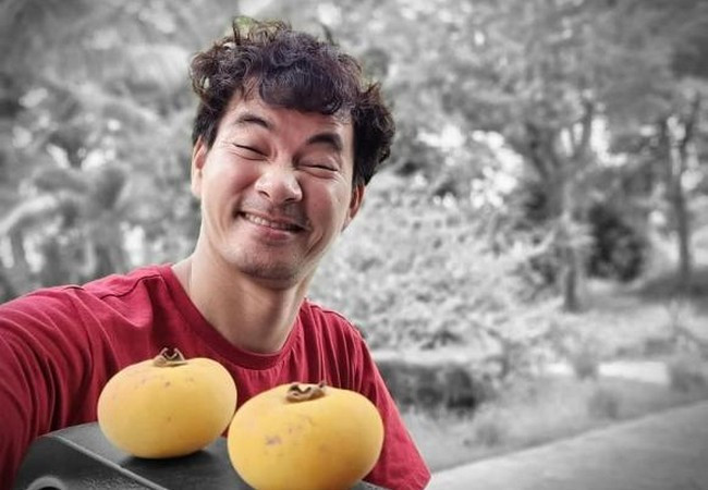 Xuân Bắc biểu cảm nhí nhố bên 2 quả thị vừa hái được trong vườn nhà.