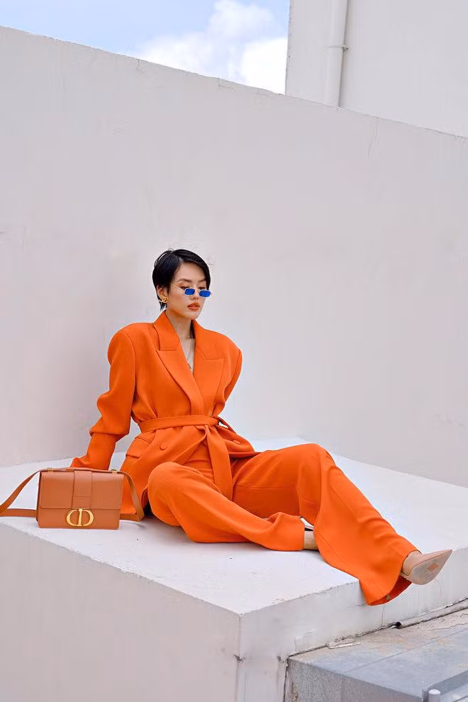 Set đồ màu cam chói lóa không làm khó được Khánh Linh khi sao Việt này chọn phụ kiện giày và túi xách tông nude mix ăn ý với mắt kính màu xanh ấn tượng.