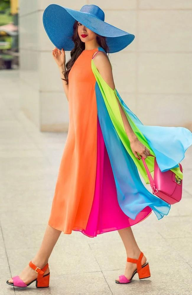 Chiếc đầm trông như 7 sắc cầu vồng bay bổng được nàng á hậu mix cùng túi xách, sandal, nón vành rộng đúng chất quý cô thời thượng.