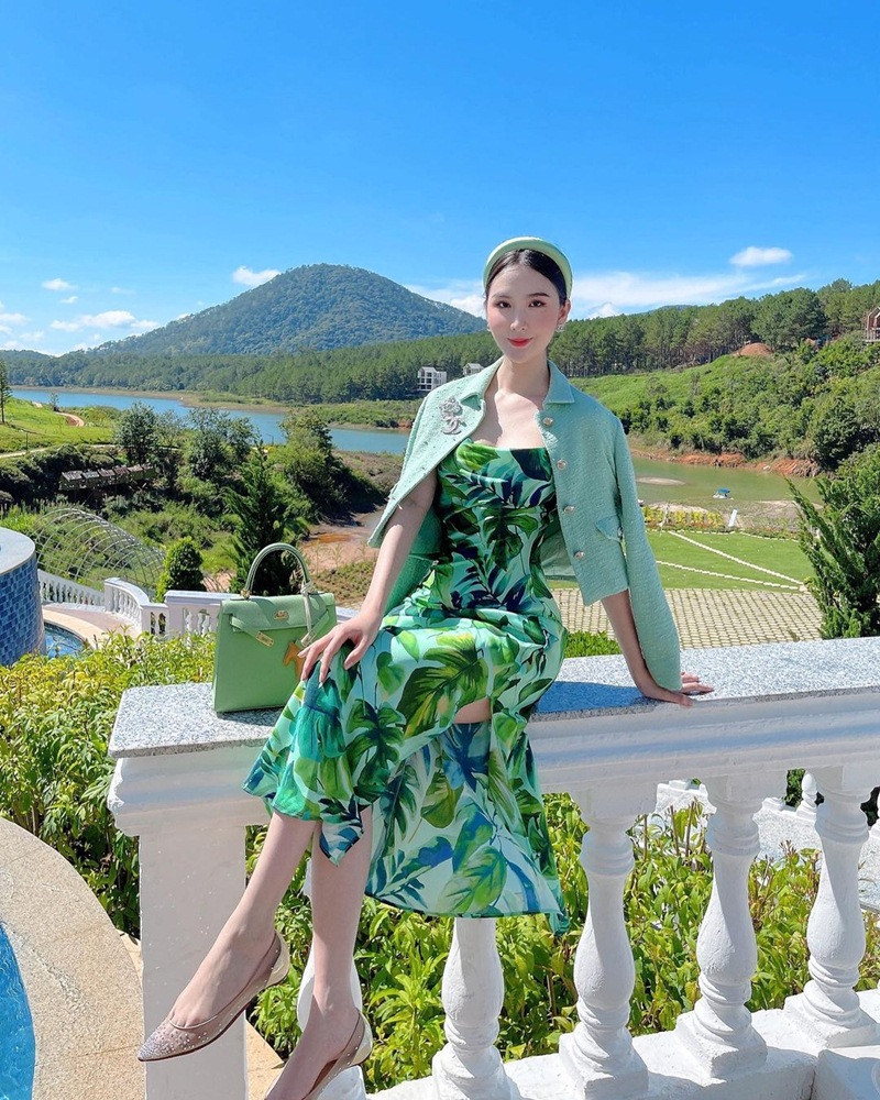 Ngọc Loan tràn đầy sức sống với đầm họa tiết, xẻ hông cao, phối hoàn hảo với áo khoác và túi Hermès tiệp màu xanh lá. Cô nàng còn mix băng đô cài tóc ton-sur-ton, điểm trang phụ kiện cài áo, khuyên tai từ Chanel.