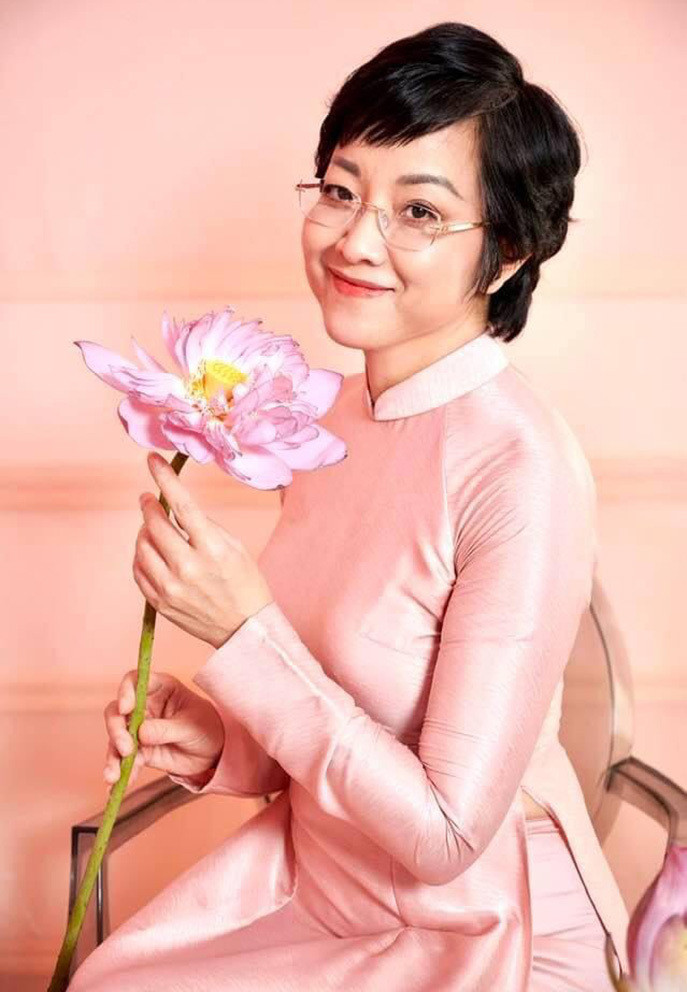 MC Thảo Vân diện áo dài hồng thướt tha tạo dáng bên sen.