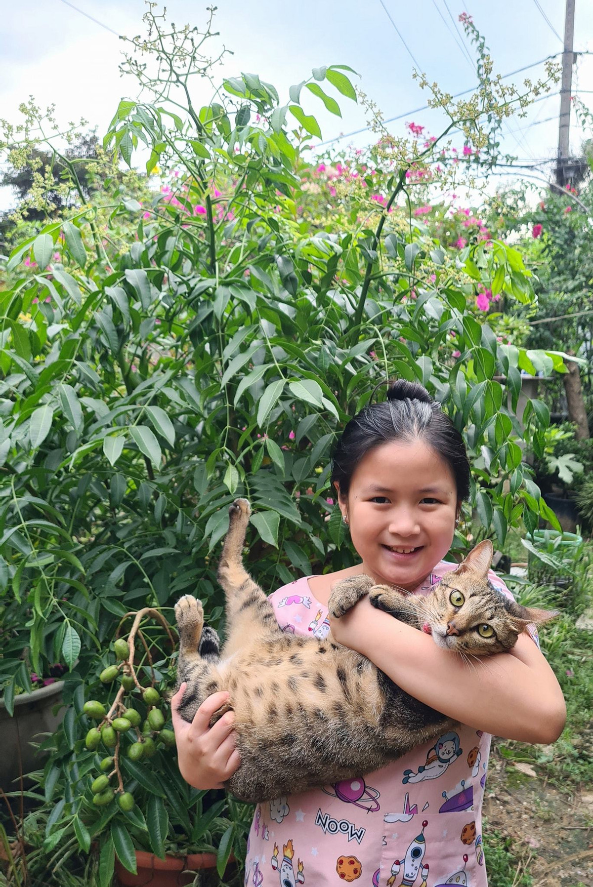 Bé Ngân Chi bế mèo ra vườn hái cóc làm nước ép.