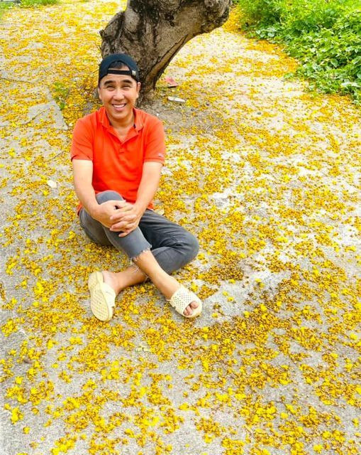 Quyền Linh đi dép tổ ông, ngồi bệt xuống đất tươi cười vì anh quan niệm: "Được cười là hạnh phúc, cười ở đâu không quan trọng".