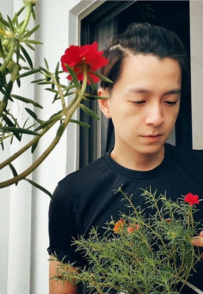 Ngô Kiến Huy tạo dáng bên khóm hoa trước ban công nhà. Anh hài hước viết: "Hoa ghen thua thắm liễu hờn kém xanh".