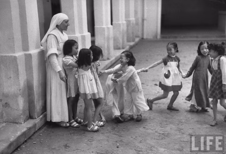 Một bà sơ người Pháp chơi đùa với trẻ em tại nhà thờ Lớn Hà Nội.